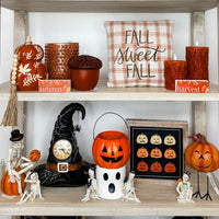 Avery Mae Boutique home decor: pumpkins, candles, fall signs, and Halloween pieces styled on a shelf.