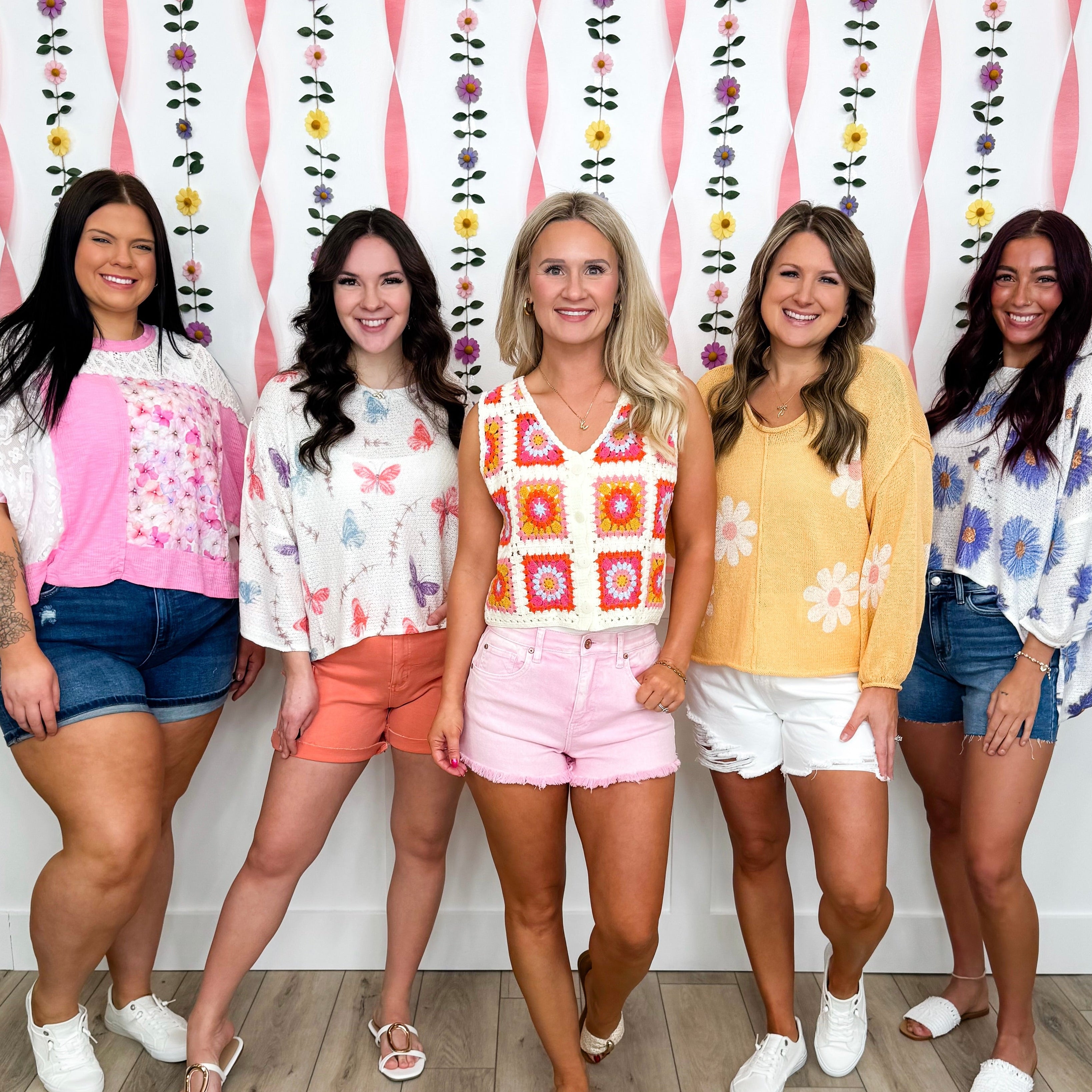 Five women posing together in size-exclusive bright spring tops.