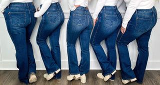 Back view of five women wearing Judy Blue bootcut jeans showing the fit and signature back pockets across regular and curvy sizes at Avery Mae Boutique