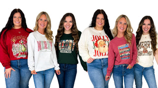 Six women in Christmas graphic sweatshirts and tees, including Whoville, Merry Christmas, Jolly Santa and a Christmas movie stack design, styled with blue jeans at Avery Mae Boutique