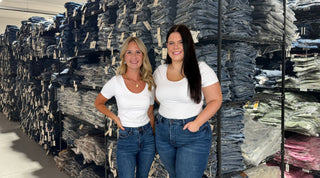 Women’s jean size conversion chart: regular size and curvy models side by side in high-rise blue jeans and white tees in the Avery Mae Boutique denim warehouse