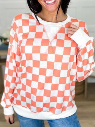Lightweight long-sleeve sweater top in orange and white checkered pattern.