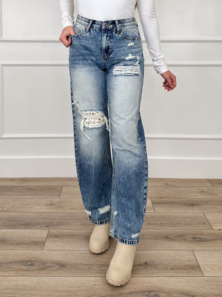 High-rise medium-wash barrel-leg jeans with distressed knees and frayed hem