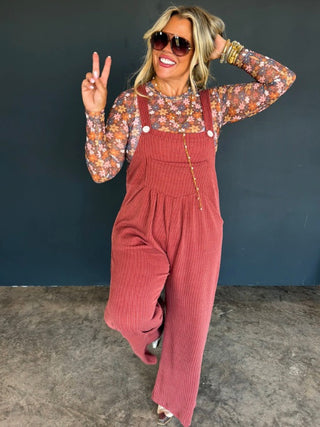 Rust orange ribbed overalls with bib front, button straps, and wide-leg pants