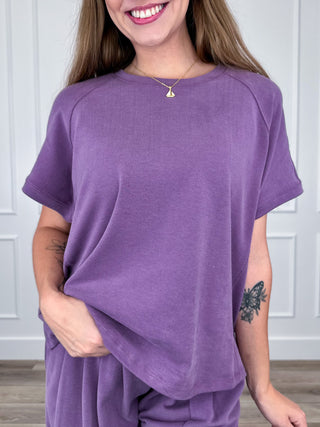 Purple short-sleeve crewneck top with wide neckline and relaxed drape