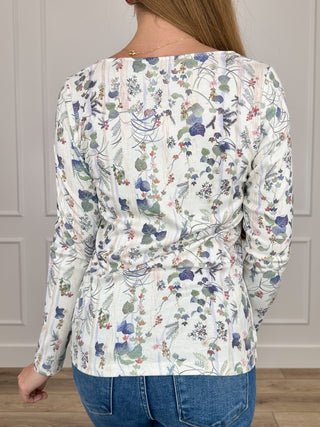 White long-sleeve knit top with floral print, scooped back, ruched waist
