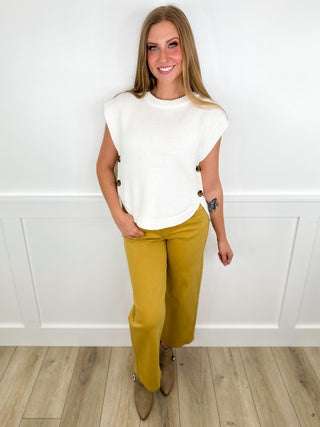 White short-sleeve top with crew neck and mustard yellow pants, full-body view