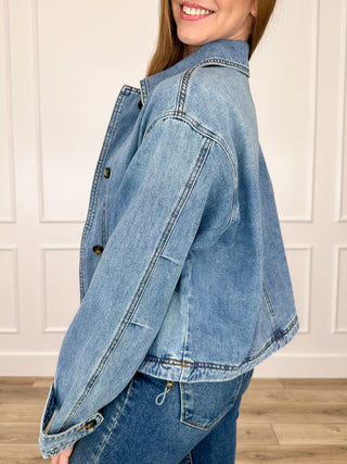 Medium wash denim jacket with button front and flap pockets, side view, long sleeves