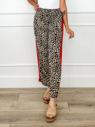 Tan leopard print high-rise pants with red side stripe, full-length