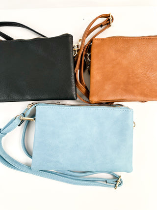 Faux leather handbags in dark, orange, and light blue with zippers and shoulder straps