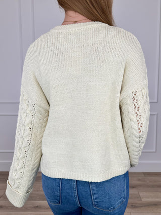 Cream cable-knit cropped sweater with long sleeves, plain back panel