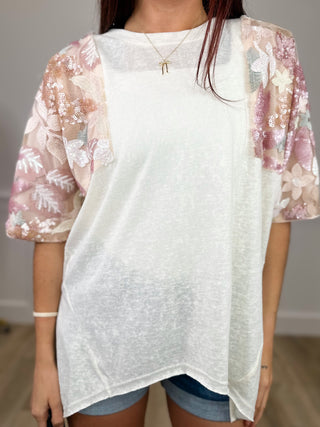 Ivory short-sleeve top with sheer pink floral puff sleeves and round neckline