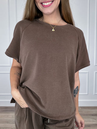 Brown short-sleeve crewneck top with relaxed drape and curved hem