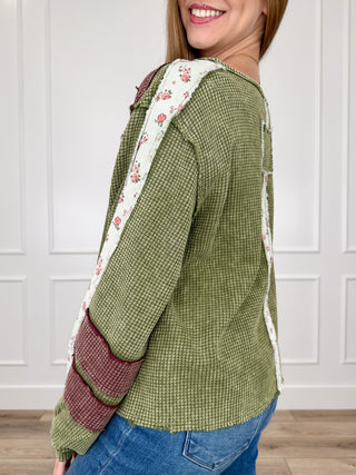 Green long-sleeve top with burgundy-and-floral contrast trim on sleeves and cuffs