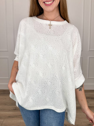 White knit short-sleeve poncho top with lace-like open-stitch texture