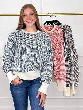 Blue-and-white knit long-sleeve sweater with ribbed cuffs and hem, buttoned round neckline.