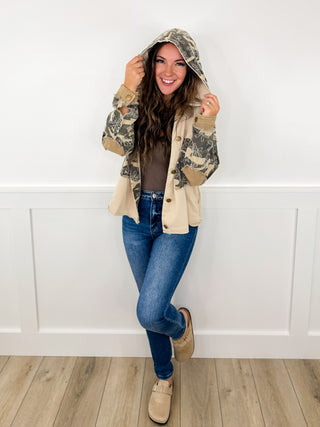 Outfit with hooded jacket, patterned sleeves, blue jeans, and tan ankle boots