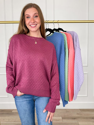 Front view: Purple knit long-sleeve sweater with textured pattern, crew neck, ribbed cuffs