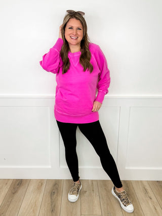 Pink long-sleeve hoodie with black leggings and low-top sneakers