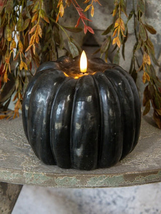 Black pumpkin-shaped LED candle with glowing white wick flame
