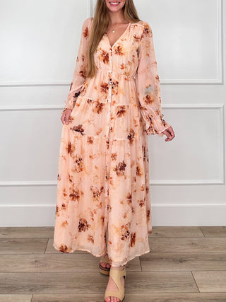 Peach floral button-up maxi dress with V-neck and flowing long sleeves, tiered skirt