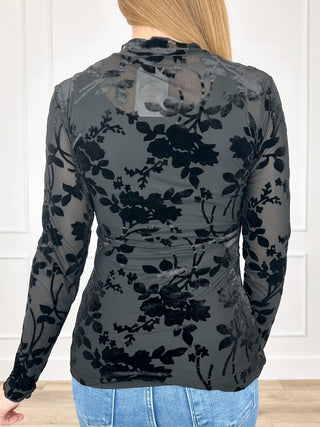 Sheer long-sleeve black top with dark floral print, back view