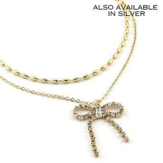 Gold dangling bow necklace with crystal-studded bow and layered chain drops.