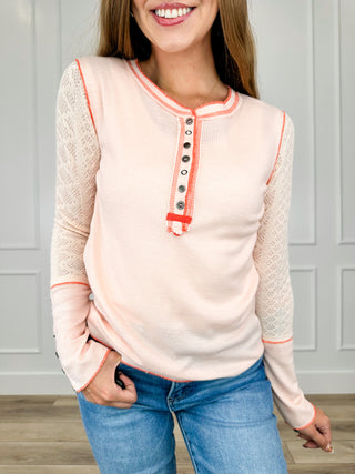 Salmon knit long sleeve henley top with button placket and orange trim at neckline