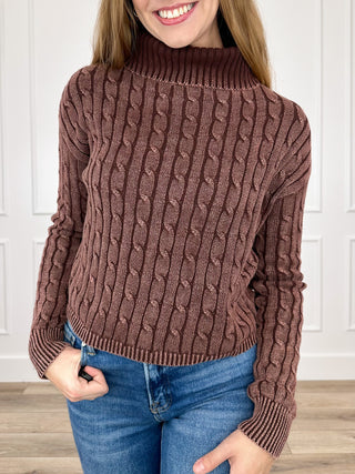 Brown cable-knit turtleneck sweater with long sleeves, ribbed collar and cuffs