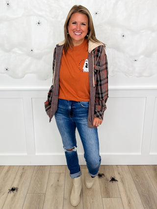 Women’s outfit: orange graphic tee, plaid open jacket, blue jeans, tan boots