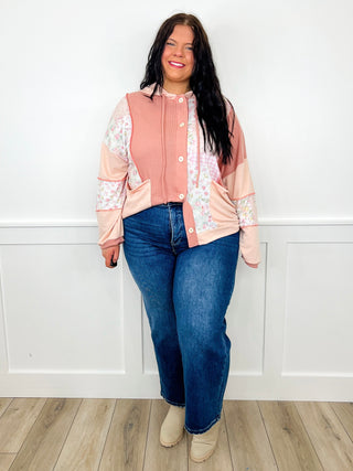 Pink zip jacket with floral sleeves, blue jeans, beige boots