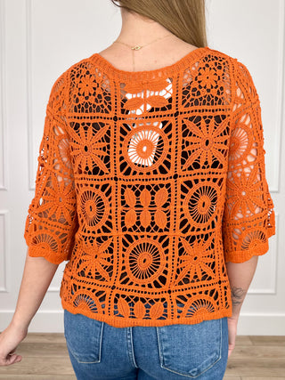 Orange crochet short-sleeve top with crew neckline and circular motif pattern
