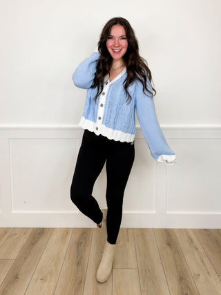 Light blue button cardigan with white hem, black leggings, beige ankle boots