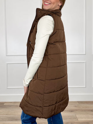 Dark brown sleeveless puffer vest with hood and horizontal quilting, long length