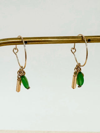 Gold hoop earrings with green teardrop charms and small bar with round disk accents.