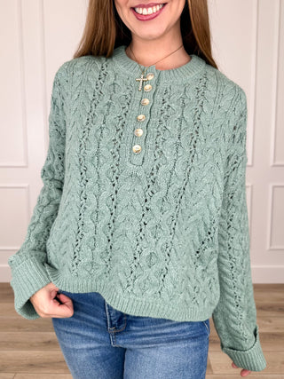 Green cable-knit cropped sweater top with long sleeves and button placket