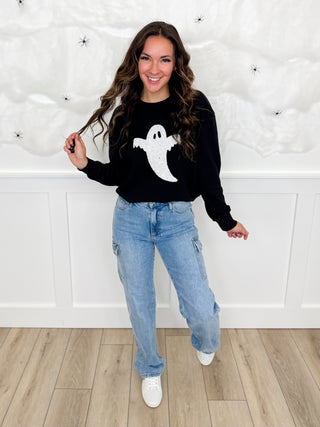 Black sweatshirt with white ghost graphic, light blue jeans, white sneakers