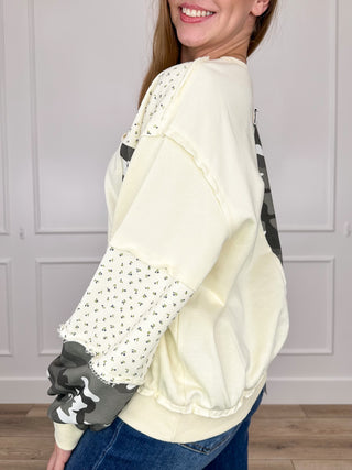 Cream long-sleeve crewneck top with camo sleeve cuff and side panel patchwork
