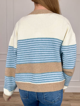 Back of cream knit cardigan with blue horizontal stripes and tan stripe band