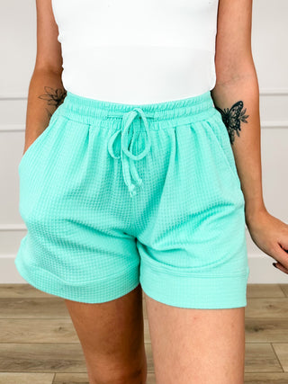 Mint green high-rise knit shorts, front view; drawstring at elastic waistband