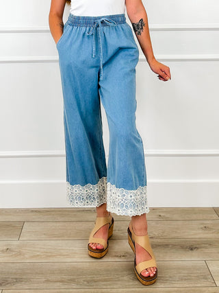 Medium-wash denim cropped wide-leg pants with lace trim hem and elastic drawstring waist