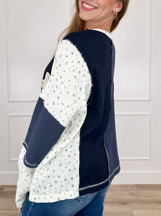 Dark blue long-sleeve top with ivory contrast sleeves and button placket trim
