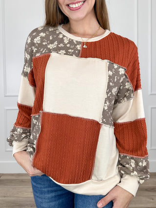 Colorblock knit long-sleeve top with cream front, rust knit panel, and floral sleeves