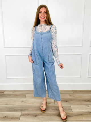 Light wash denim jumpsuit with wide legs, front bib, and floral print sleeves