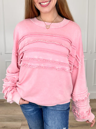 Pink long-sleeve cotton top with layered ruffle chest bands and ruched sleeve cuffs