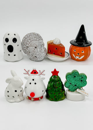 Assorted ceramic light-up shelf sitters, including ghost, bunny, football, and candy-shop shapes.