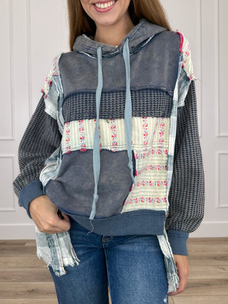 Charcoal hooded long-sleeve top with drawstring, front pocket, and multicolor patch sleeves
