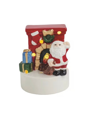 Light-up ceramic Santa beside a fireplace with stockings and presents