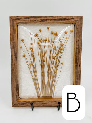Framed dried flower pod wall decor with tall straw stems and round golden seed pods