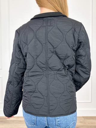 Black quilted long-sleeve jacket, back view with stand collar and zip closure